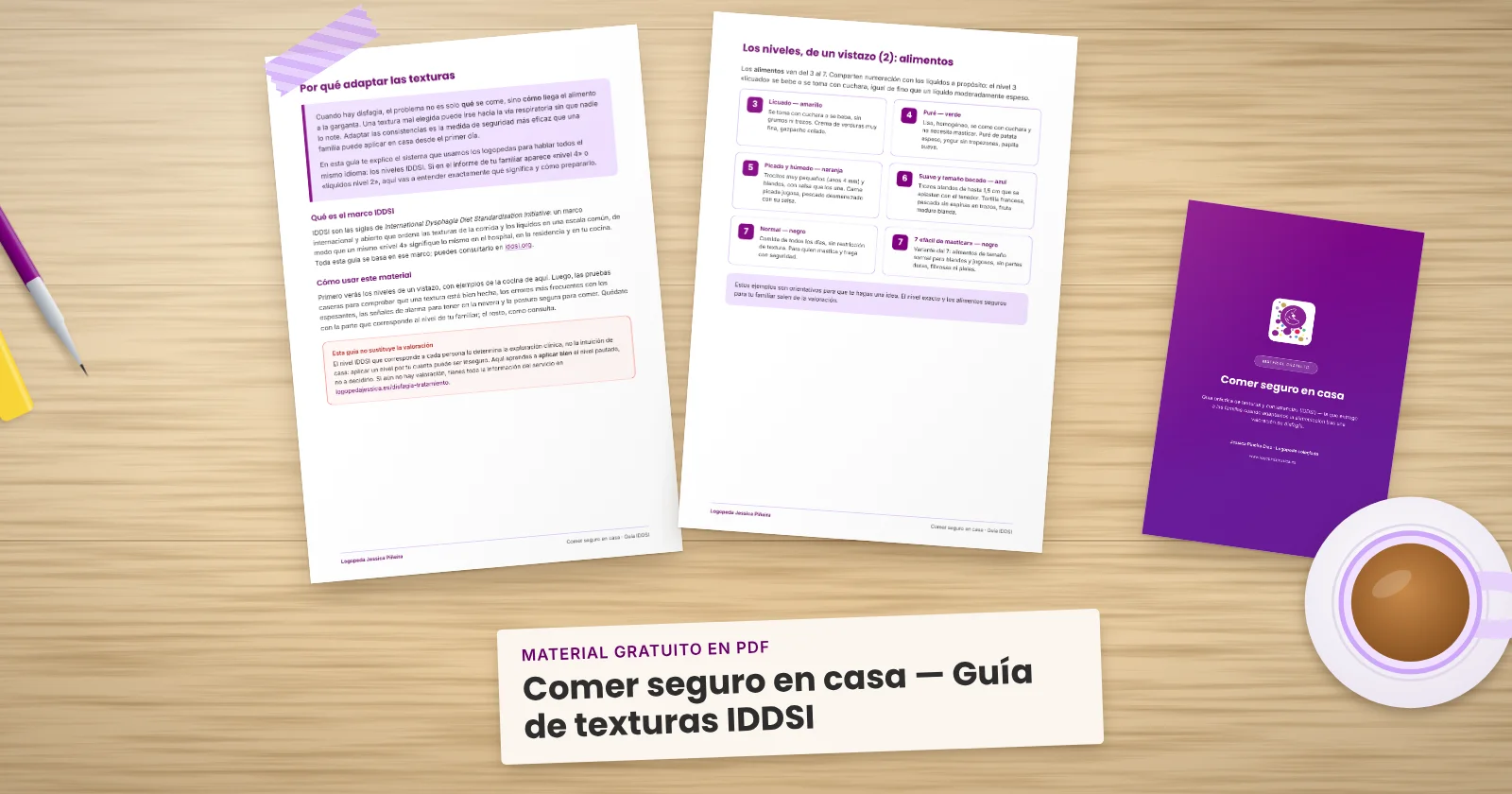 Dos páginas impresas de «Comer seguro en casa — Guía de texturas IDDSI» sujetas con cinta washi sobre una mesa de madera, con la portada asomando. Alrededor, una etiqueta de papel con el título, un bolígrafo, un fluorescente y una taza de té.